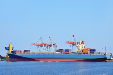 Fototapeta premium Container stack and ship under crane bridge