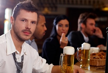 Young businessman having beer in pub