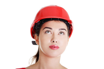 Confident female worker in helmet looking up.