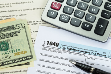 Tax form with pen, calculator, and dollar banknote taxation conc