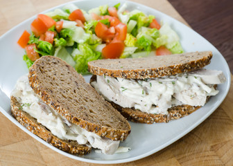 Two chicken sandwich on a dish with green salad