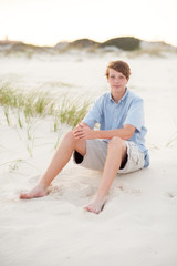 Fototapeta na wymiar teen boy sitting in the sand on the beach