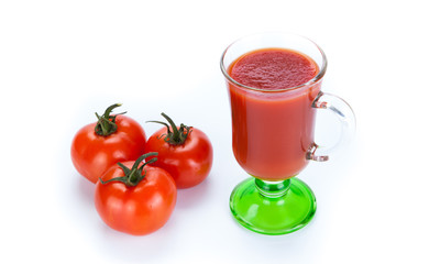 red tomatoes and glass of tomato juice on a white background
