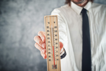 Businessman holding thermometer with temperature on Zero value