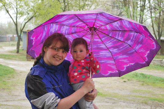 Spring rain is mother with daughter standing under an umbrella