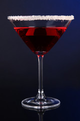 Red cocktail in martini glass on dark blue background