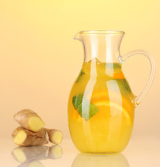 Orange lemonade in pitcher on yellow background