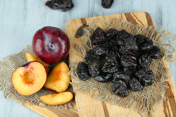 Fresh and dried plums  on napkin, on wooden background