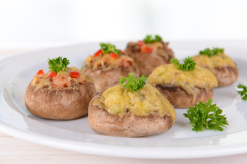 Stuffed mushrooms on plate on table on light background