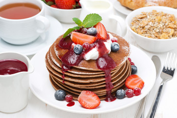 breakfast with pancakes with cream, fruit sauce, fresh berries