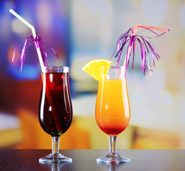 Glasses of tasty cocktails on bright background