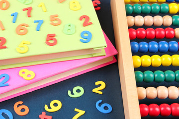 Colorful numbers, abacus and books on school desk background