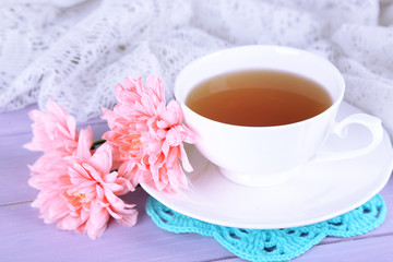 Pink chrysanthemums and cup of tea on wooden table