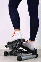 Woman doing exercise on stepper. Close-up on legs.