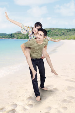 Boyfriend giving piggyback ride at beach