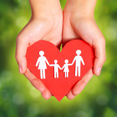 Paper Family and Heart in Hands over Green Sunny Background