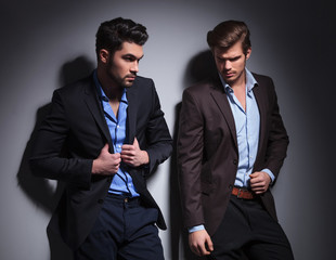 one looking away and one pulling his suit's collar
