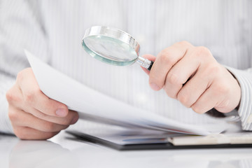 Businessman looking through a magnifying glass