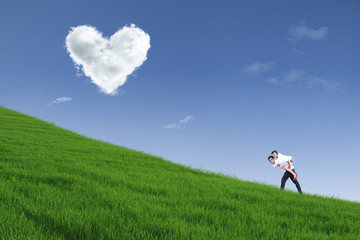 Guy giving piggyback ride on hill under heart cloud