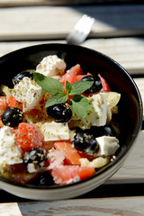Mixed vegetables salad with cheese in black bowl