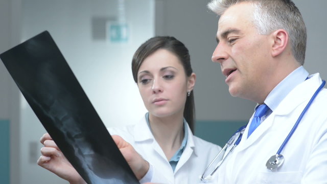 Doctor and assistant looking at patient's x-ray and pointing