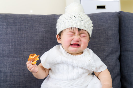 Little girl crying with bread holding on hand