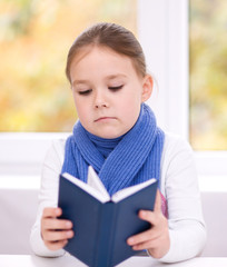 Little girl is reading a book