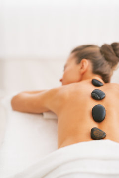 Young woman receiving hot stone massage. rear view
