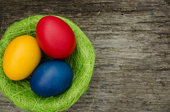 Colorful easter eggs  in straw nest on a wooden table