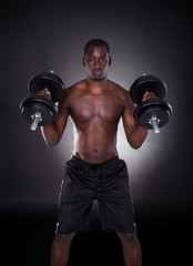 Fototapeta na wymiar Young African Man Working Out With Dumbbells