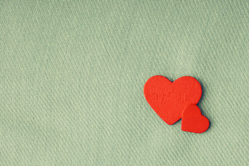 Red wooden decorative hearts on gray cloth background.