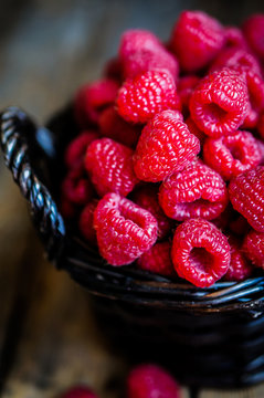 Raspberries in a basket on rustic wooden background
