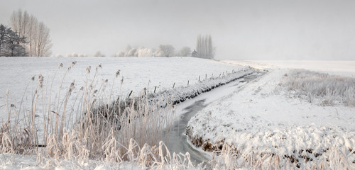 Snowfall over a rural area with a meandering ditch