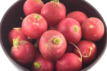 Many red radishes in purple bowl closeup isolated on white