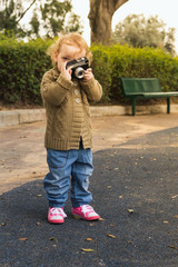 Adorable little baby holding vintage camera. Photo in old color