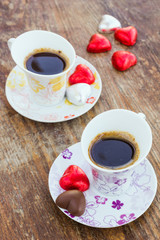 Two cups of coffee with heart shaped candy