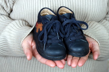 Mutterhande halten Babyschuhe