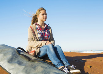 Teenage girl at the beach with her surfboard 