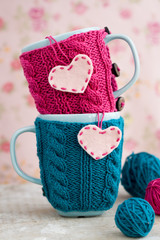 Two blue cups in blue and pink sweater with felt hearts