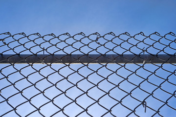 Chain link fence with bar against blue sky