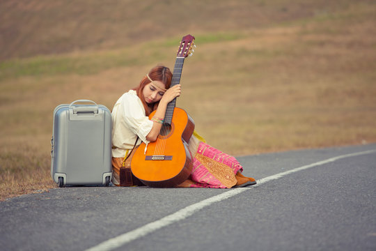 Hippie woman sitting on a countryside road