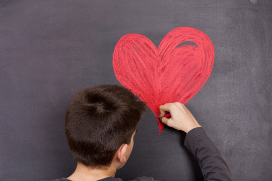 child drawing a red heart on the Board