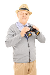 Senior gentleman holding binoculars and looking at camera