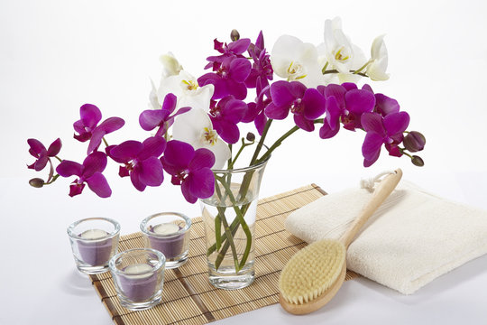Wellness mit Massagebürste, Handtuch, Kerzen und Orchidee