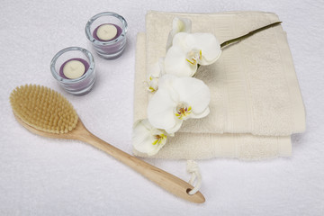 Fototapeta na wymiar Wellness mit Massagebürste, Handtuch, Kerzen und Orchidee