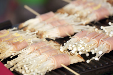 Flammulina Velutipes Mushrooms and bacon on grill.