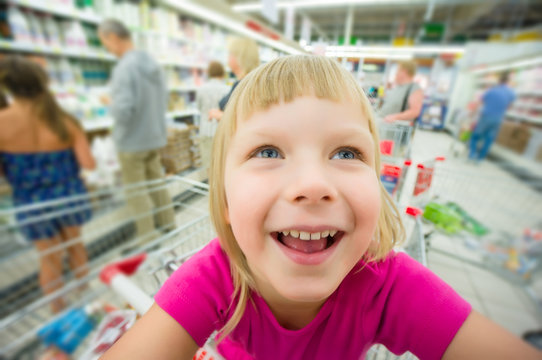 Adorable girl at shopping cart select products in supermarket