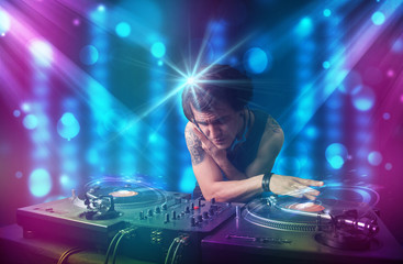 Dj mixing music in a club with blue and purple lights