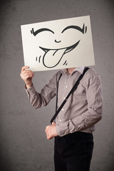 Businessman holding a paper with funny smiley face in front of h