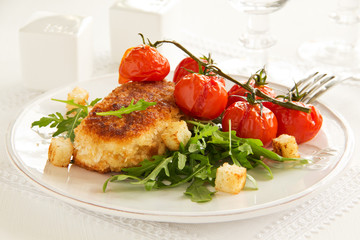 Chicken cutlet with grilled tomatoes and salad.